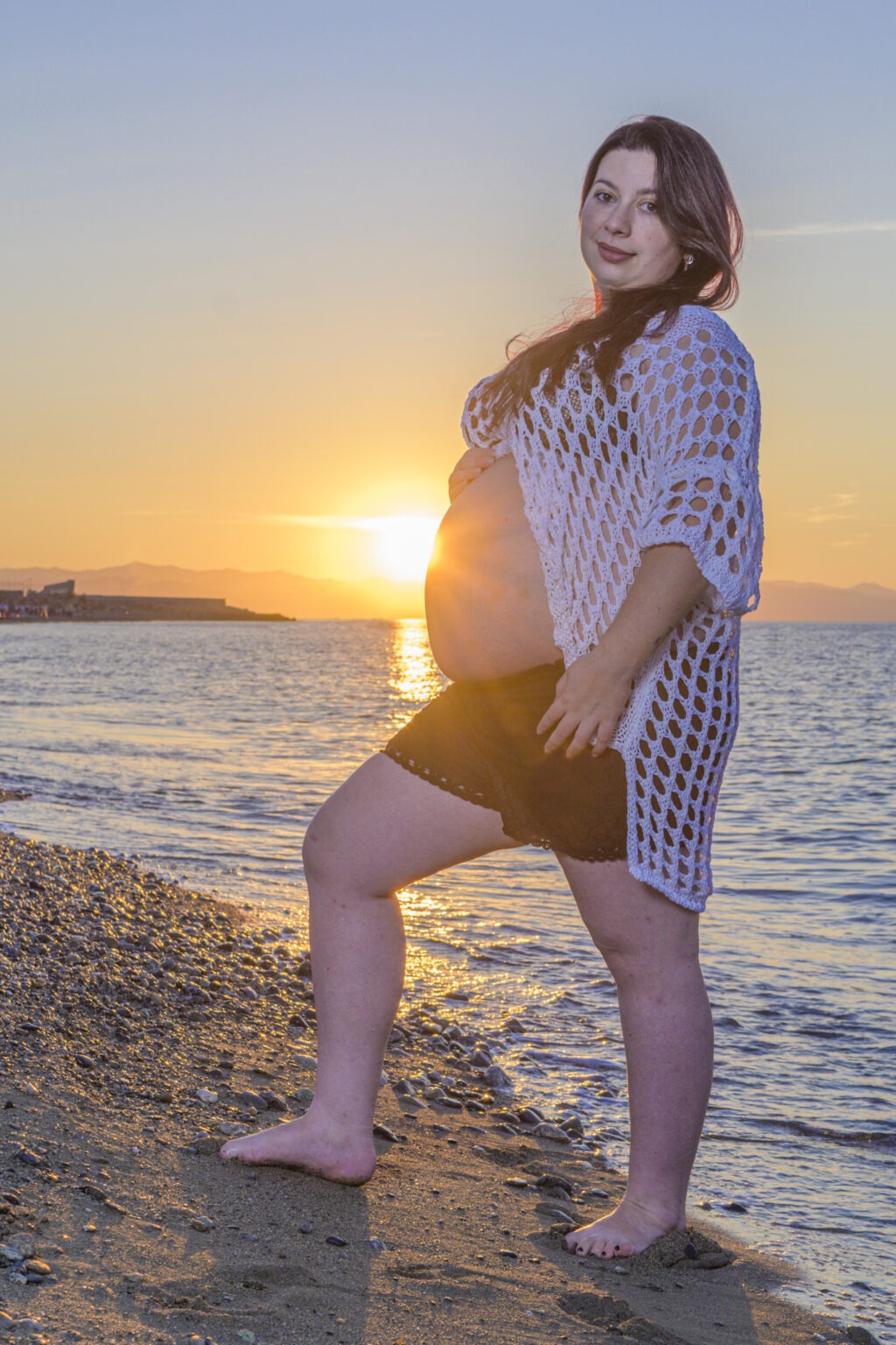 Ragazza incinta sulla spiaggia con il sole sullo sfondo - scatto di Ivan D'Amico Fotografo