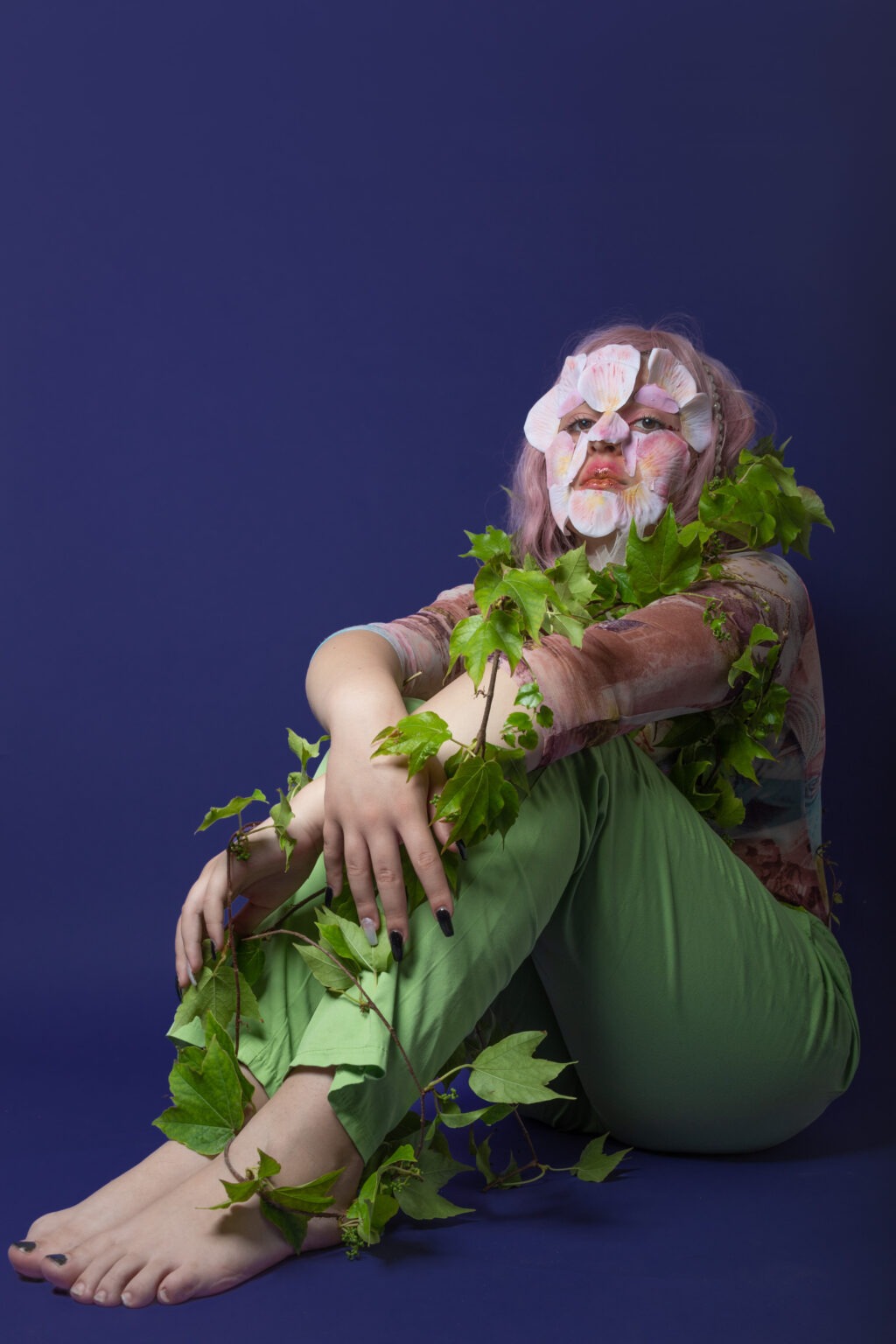 Ragazza truccata da pianta con petali in faccia seduta a terra - Scatto Portfolio